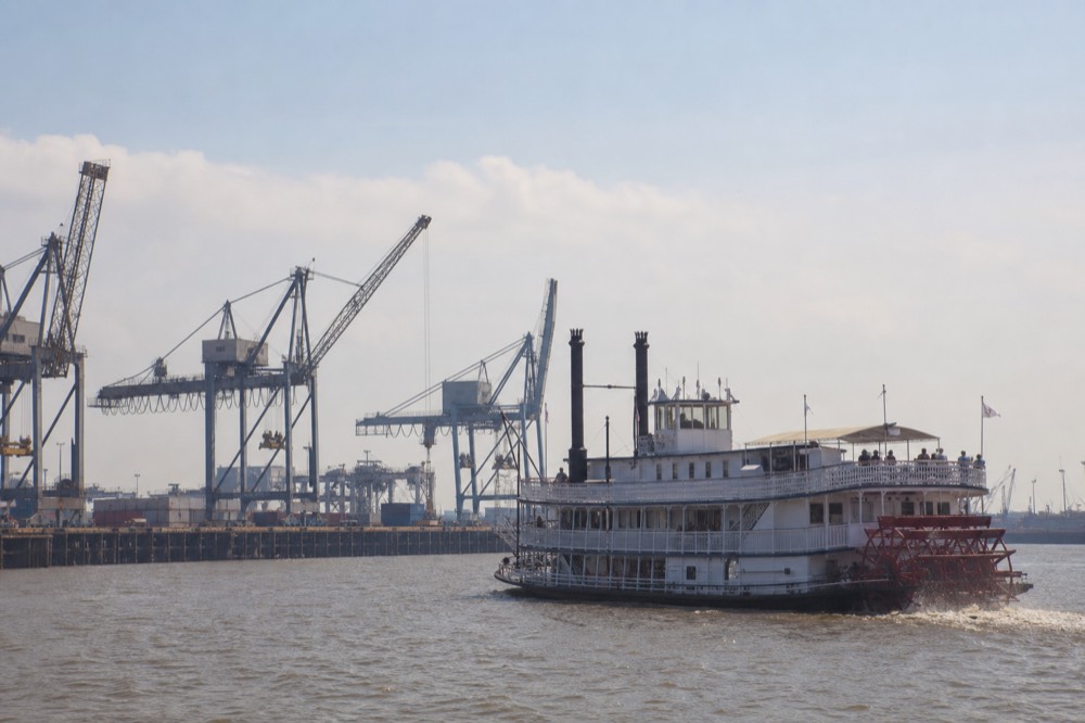 Sternwheeler passing container cranes and working wharves on the Mississippi in bright afternoon light