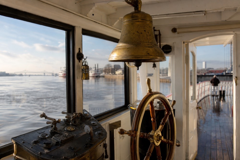 Historic ship's bell and brass steering wheel in the pilot house of a Mississippi sternwheeler