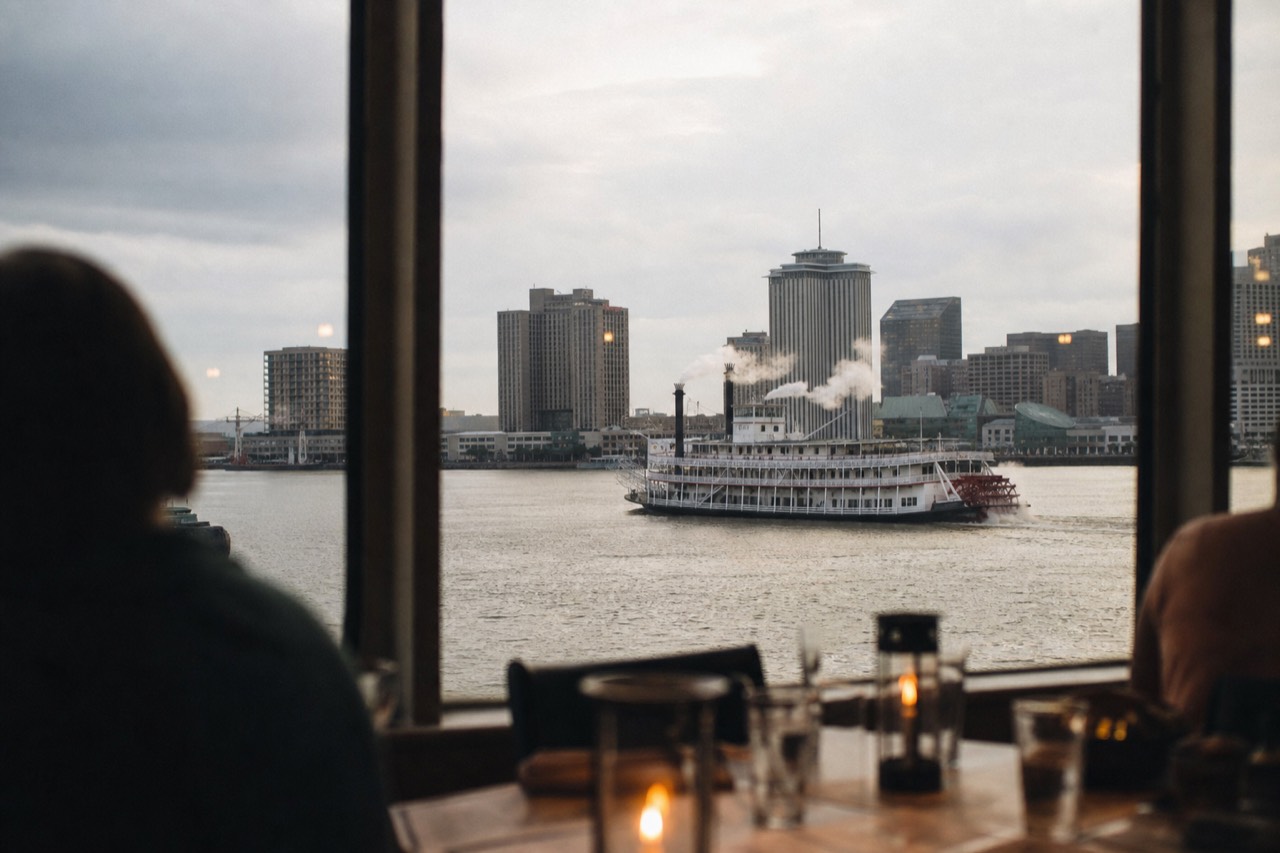 Sternwheel steamboat under way on the Mississippi with steam rising from her stacks and the French Quarter skyline behind