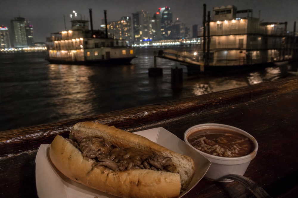 A hot roast beef po-boy and a bowl of red beans on a paper tray at a riverboat bar counter