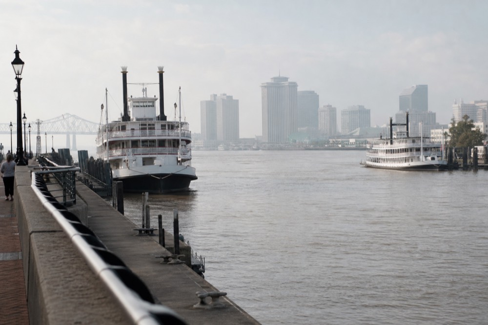 Two white excursion riverboats moored a few hundred metres apart along the New Orleans riverfront promenade