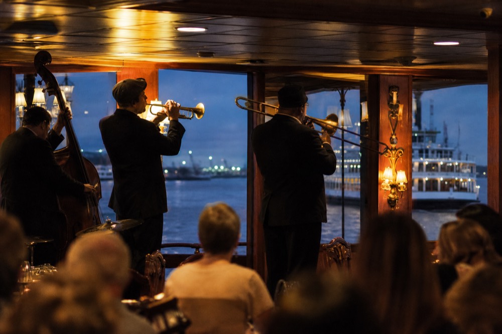 Traditional jazz band with trumpet, trombone and upright bass playing at the front of a riverboat dining room