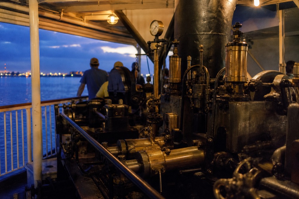 Brass and iron steam engine machinery seen from a public viewing area aboard a working sternwheeler