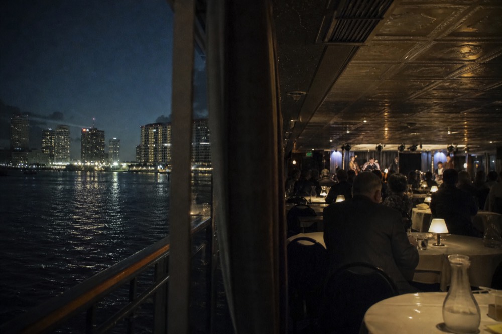 Evening dining room on a riverboat with white tablecloths, warm lamps and the band set up at the far end