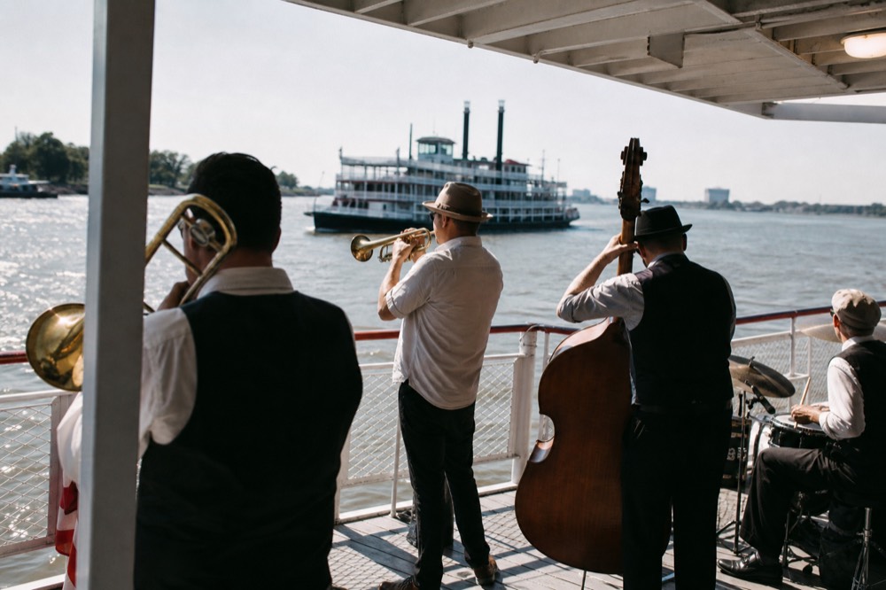 Five-piece traditional jazz band with trumpet, trombone and upright bass playing on a riverboat deck