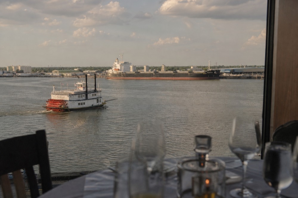 Wide view of the Mississippi crescent bend at New Orleans with a small excursion paddlewheeler and a large ship at the port terminal beyond