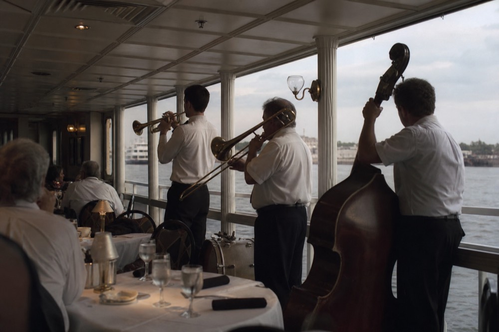 Four-piece traditional jazz band with trumpet, trombone and upright bass performing in a riverboat dining room